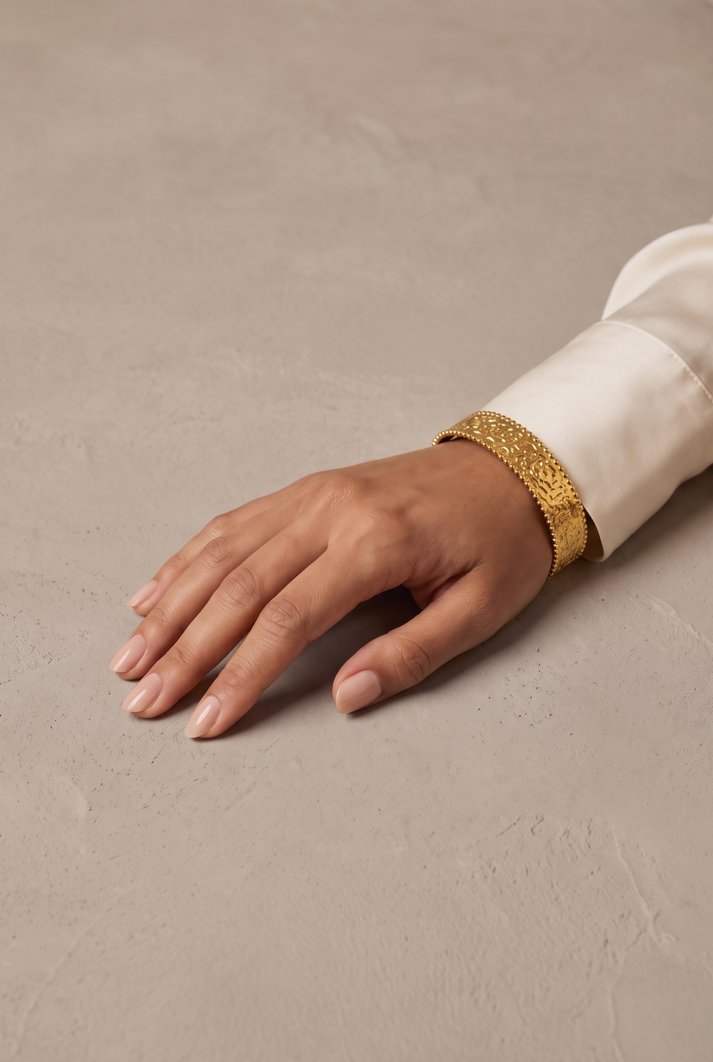 Hammered beaded-edge cuff bangle in gold worn on the wrist